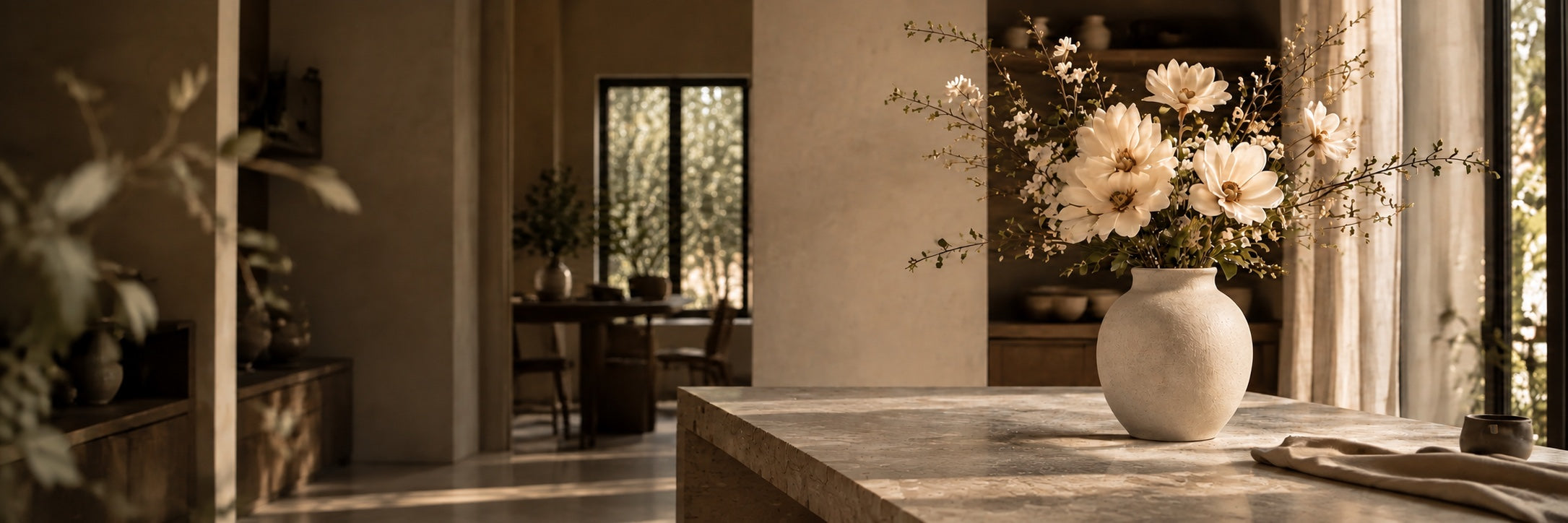 Ivory botanicals in a warm-white matte stoneware vase on a sunlit travertine table in an Orlando-inspired studio